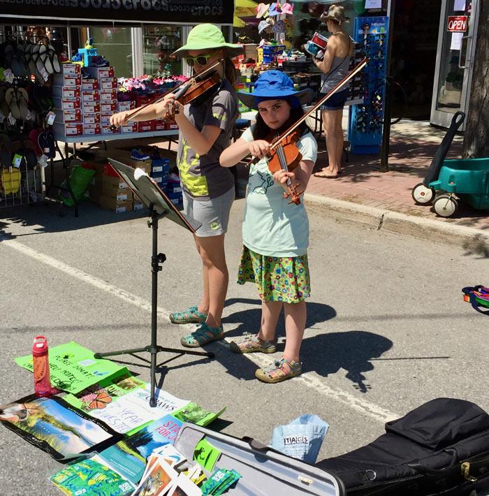 Deux jeunes filles jouant du violon dans la rue