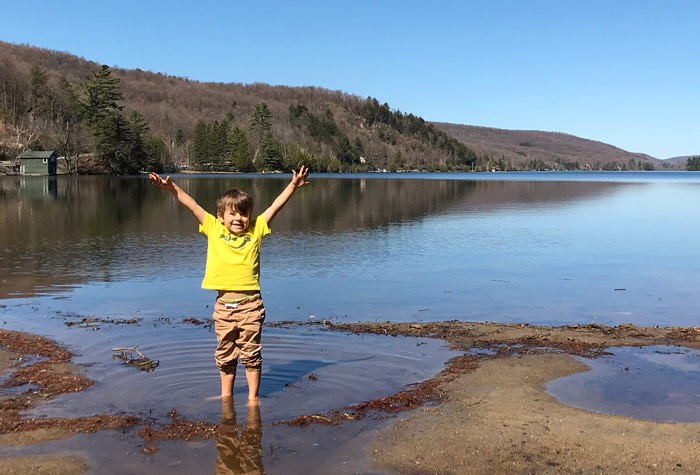 Jeune garçon les pieds dans l'eau au bord du lac Meech.